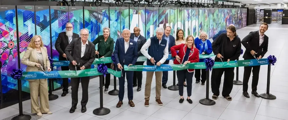 Группа исследователей и лидеров отрасли собралась перед суперкомпьютером Aurora. Они позируют перед ним, перерезая ленточку в честь открытия машины