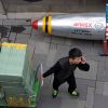 На китайско-американском фронте — артподготовка (Мужчина с тележкой возле скамейки в виде ракеты с флагом США рядом с магазином в Пекине) Мужчина с тележкой в…