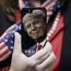 TAC: США превратились в страну-посмешище (Женщина держит телефон с фотографией Дональда Трампа во время предвыборной кампании в США | © AP Pho…) Женщина держит телеф…